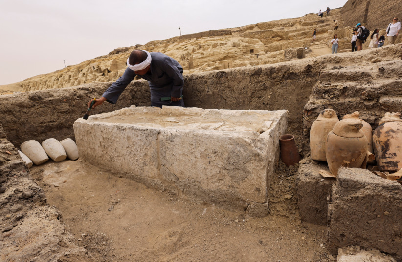  A worker brushes off the dust at the embalming workshop site for humans at the newly discovered site where two embalming workshops for humans and animals, two tombs and a collection of artefacts were also found, near Egypt's Saqqara necropolis, in Giza, Egypt May 27, 2023 (credit: REUTERS/AMR ABDALLAH DALSH)