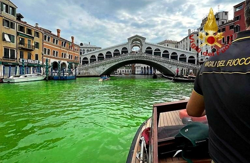 Venice's waters turn green due to an unknown substance near the Rialto Bridge, in Venice, Italy in this handout image released May 28, 2023. (credit: VIGILI DEL FUOCO/HANDOUT VIA REUTERS)