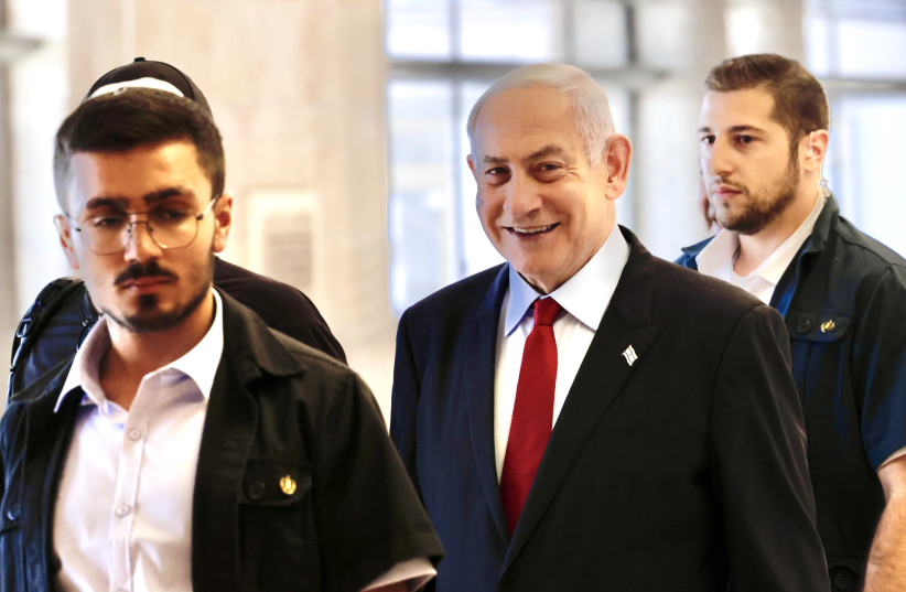 Prime Minister Benjamin Netanyahu is seen smiling as he is escorted to a faction meeting in the Knesset on May 29, 2023 (credit: MARC ISRAEL SELLEM)