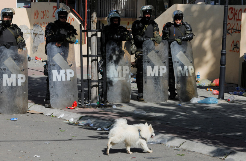  A dog walks by Polish Kosovo Force (KFOR) soldiers standing guard at a municipal office in Zvecan, Kosovo May 30, 2023. (credit: REUTERS)