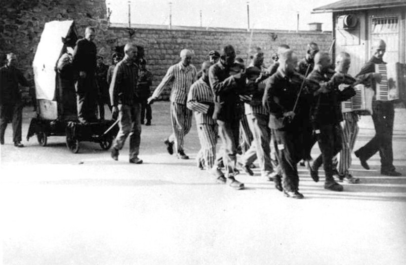  AT MAUTHAUSEN, inmate Hans Bonarewitz is led to execution, pulled on a cart with the crate inside which he attempted to escape. He is accompanied by the camp orchestra, which was forced to continuously play “J’attendrai ton retour” (I shall wait for your return).  (credit: Wikimedia Commons)