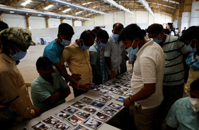   People look at pictures to identify the bodies of victims of a train collision, at a temporary mortuary created in a business park, following the train collision in Balasore district in the eastern state of Odisha, India, June 4, 2023. (credit: REUTERS/ADNAN ABIDI)