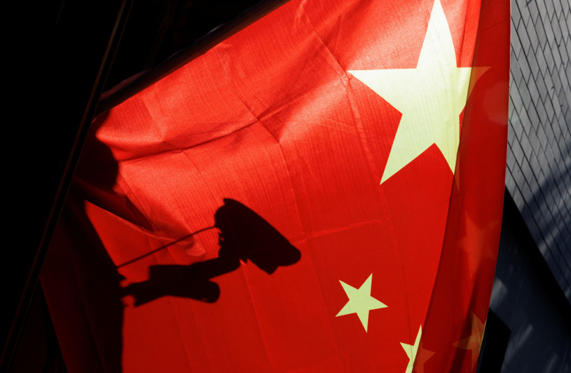  A surveillance camera is silhouetted behind a Chinese national flag in Beijing (credit: REUTERS)
