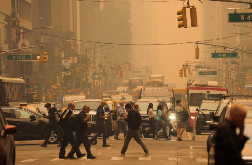  People walk at 6th Avenue as haze and smoke caused by wildfires in Canada blanket New York City, New York, US, June 7, 2023 (credit: Andrew Kelly/Reuters)