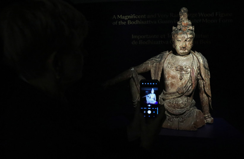  Head of Chinese Art Caroline Schulten at Bonhams auction house takes a picture of a rare Buddha statue, believed to be from the 12th century in China, before its auction in Paris, France, June 9, 2023. (credit: REUTERS/Yiming Woo)