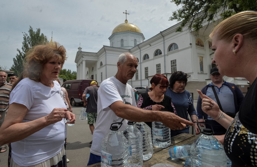  Local residents take drinking water, amid Russia's attack on Ukraine, after the Nova Kakhovka dam breached, in Kherson, Ukraine June 10, 2023. (credit: REUTERS)