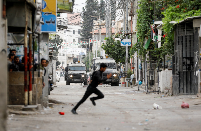  A Palestinian runs amid clashes with Israeli troops during an Israeli raid in Nablus in the West Bank June 13, 2023. (credit: RANEEN SAWAFTA/REUTERS)