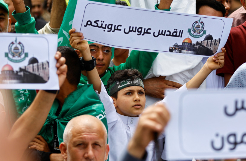   boy holds a placard as Palestinian Hamas supporters attend a rally against visits by Israeli right wing groups to Al-Aqsa mosque, in Khan Younis in the southern Gaza Strip May 26, 2023 (credit: REUTERS/IBRAHEEM ABU MUSTAFA)