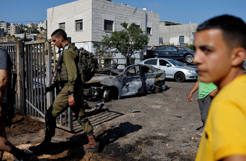 A Palestinian man checks burned vehicles after an attack by Israeli settlers near Ramallah in the Israeli-occupied West Bank, June 21, 2023.