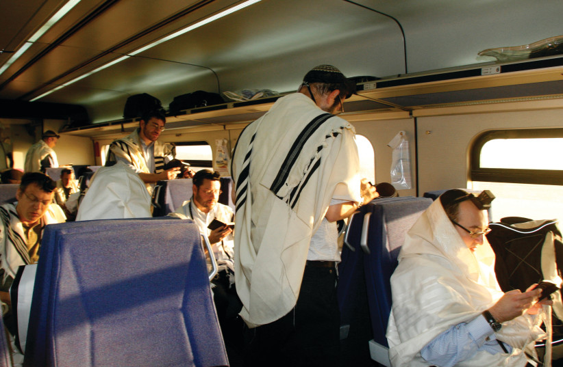  MEN RECITE morning prayers on a train between Jerusalem and Tel Aviv. Daily prayer allows us to consciously express gratitude for our livelihoods and cognitive abilities, the writer notes. (credit: LARA SAVAGE/FLASH90)