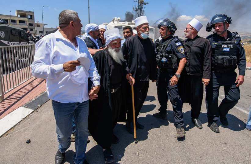 Druze protest while police guard during a protest against the construction of a new wind farm in the Druze village of Mas'ada, in the Golan Heights, June 21, 2023.