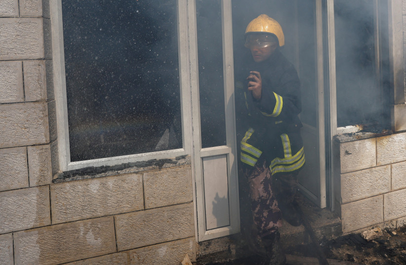  A Palestinian Civil Defence member looks on, as smoke leaves a building, after an attack by Israeli settlers, near Ramallah, in the West Bank, June 21, 2023. (credit: MOHAMAD TOROKMAN/REUTERS)
