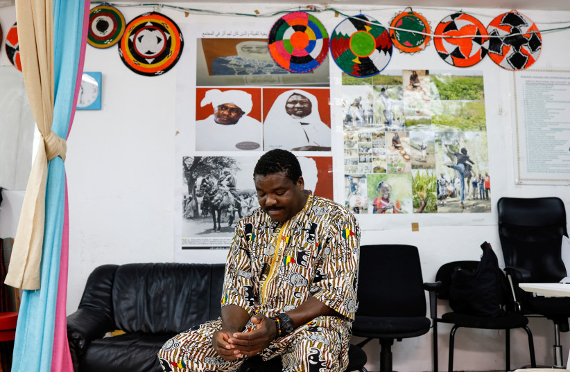  Boukary Mandela, 43, an asylum seeker and truck driver from Darfur in Sudan sits in front of pictures of the current and past sultans of the Masalit tribe in the Masalit tribe community centre in southern Tel Aviv, Israel June 24, 2023. (credit: REUTERS/AMIR COHEN)
