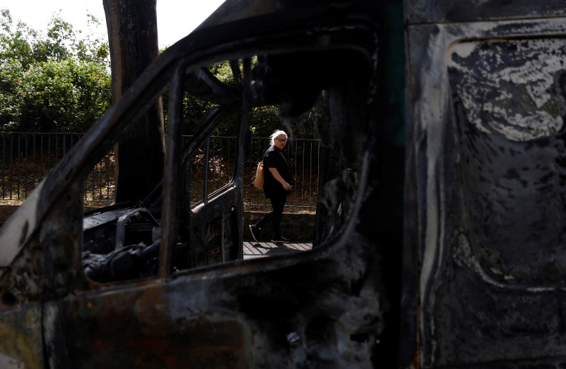  A woman walks in a street past a car, burnt during clashes between youths and police, the day after the death of a 17-year-old teenager killed by a French police officer during a traffic stop, in Nanterre, Paris suburb, France, June 28, 2023 (credit: REUTERS)