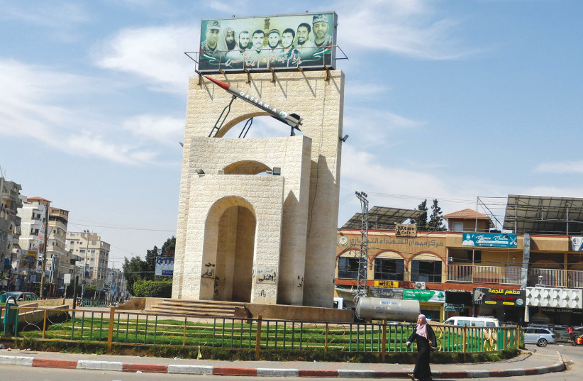 A Palestinian woman walks in front of a roundabout with a model of a Qassam rocket, in Rafah, southern Gaza Strip on June 7, 2023.