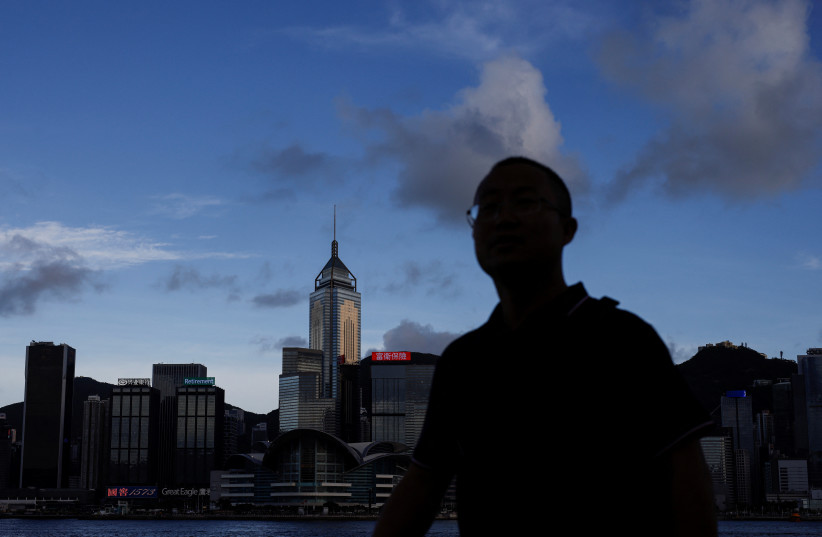  A man walks along the waterfront in front of Victoria Harbour, with the iconic skyline buildings as a backdrop, in Hong Kong, China June 28, 2023 (credit: REUTERS/TYRONE SIU)