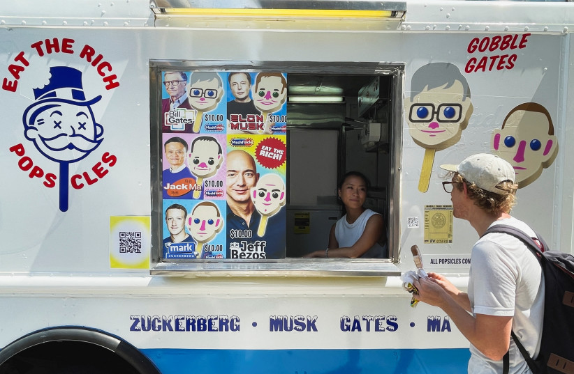 Customer Jeremy Klitzman, looks on to the ''Eat the Rich'' popsicle ice cream truck, created by Brooklyn artist collective MSCHF, in Brooklyn, New York, July 12, 2022.  (credit: REUTERS/ROSELLE CHEN)