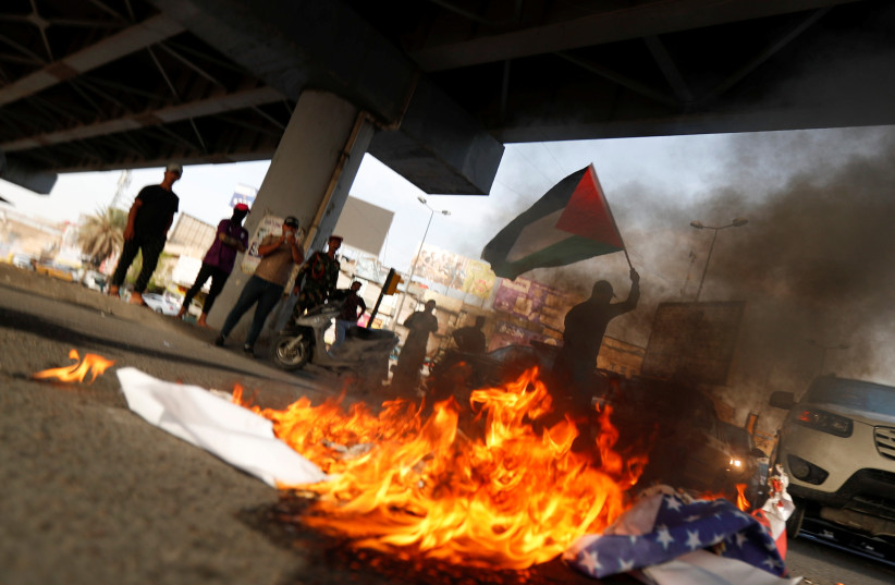Members of Kataib Hezbollah paramilitary group burn Israeli and U.S. flags ahead of the annual Quds Day, or Jerusalem Day, during the Muslim holy month of Ramadan in Baghdad, Iraq May 6, 2021. (credit: THAIER AL-SUDANI/REUTERS)