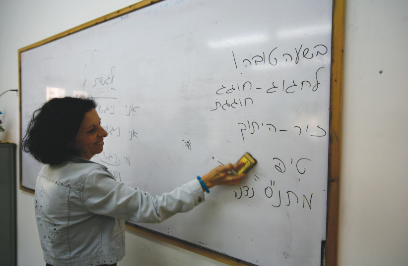  An ulpan teacher writes on a whiteboard in Hebrew. (credit: FLASH90)