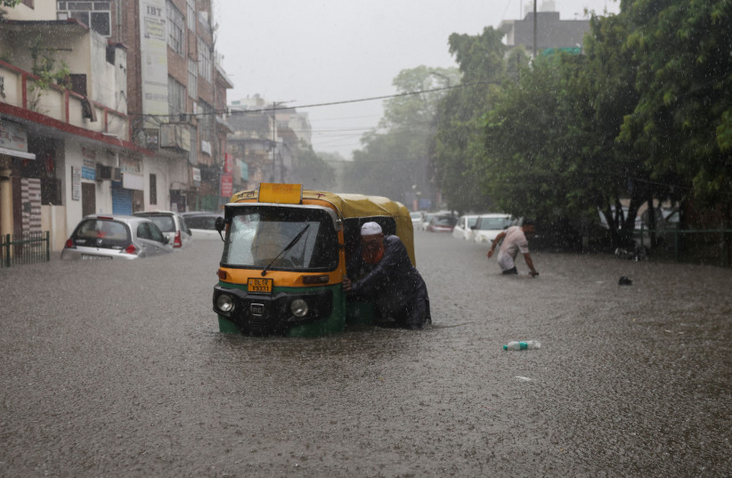  A man pushes his rickshaw in a flooded street after heavy rains in New Delhi, India, July 8, 2023. (credit: REUTERS/ANUSHREE FADNAVIS)