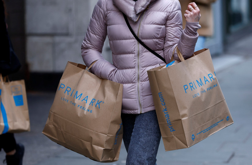  A woman carries Primark shopping bags on Oxford Street, in London, Britain, January 16, 2023.  (credit: REUTERS/PETER NICHOLLS)