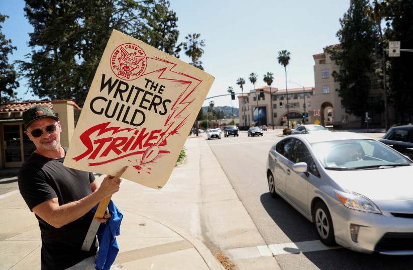  Board member of the Writers Guild of America (WGA) Dante Harper holds a protest sign that was used during the first WGA strike, in Burbank, California, US, May 2, 2023.  (credit: MARIO ANZUONI/REUTERS)