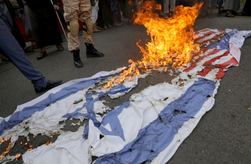  US and Israeli flags burn as people rally to denounce the burning of the Koran in Sweden and the Israeli military operation in the West Bank city of Jenin, in Sanaa, Yemen July 4, 2023.  (credit: REUTERS/KHALED ABDULLAH)