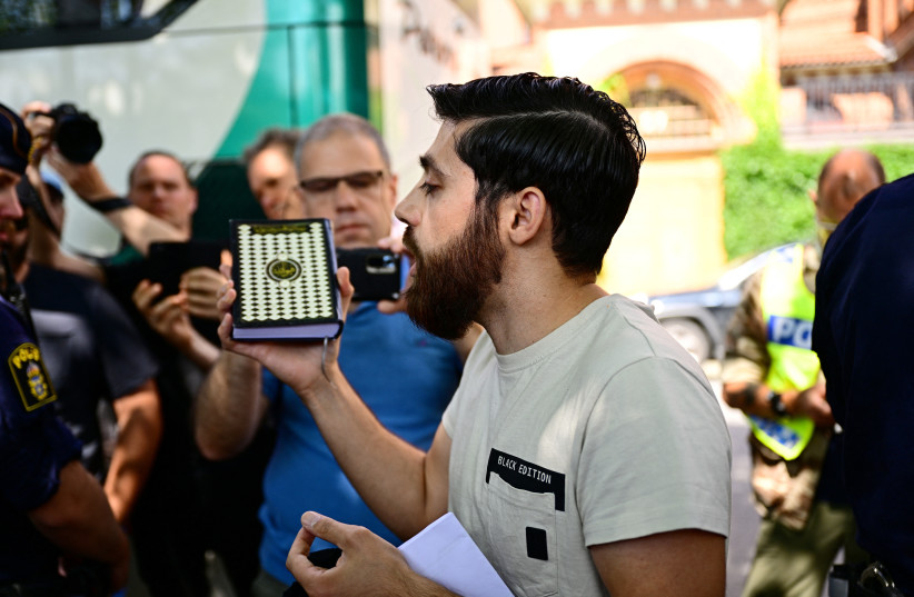   A person who has been given permission by the police for a public gathering to burn a Torah and a Bible outside the Isaeli embassy, holds a Koran in his hand after choosing not to burn the books, according to local media, in Stockholm, Sweden July 15, 2023. (credit: TT NEWS AGENCY/MAGNUS LEJHALL/VIA REUTERS)