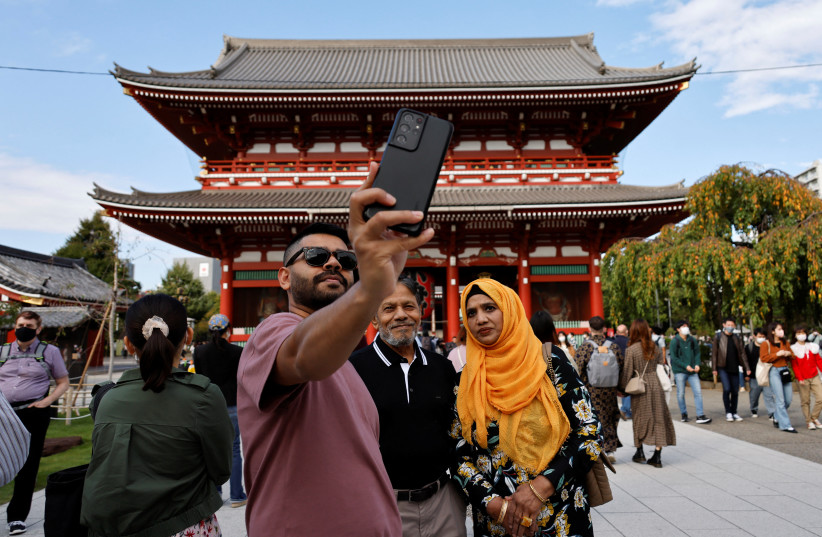  Tourists from the US take selfie photos at Nakamise street leading to Senso-ji temple, at Asakusa district, a popular sightseeing spot in Tokyo, Japan, October 19, 2022.  (credit: REUTERS/ISSEI KATO)