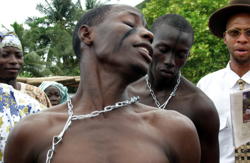 Nigerian Kehinde Avose wears chains on his neck while re-enacting the days of slavery for American visitors in the former slave port of Badagry town south-west Nigeria August 25, 2002. More than fifty black Americans, including seven mayors, are in Lagos for the Second Black Heritage Festival. (credit: REUTERS/George Esiri GE/CLH/)