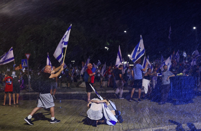 Israeli security forces use a water cannon as protesters hold flags during a demonstration against Israeli Prime Minister Benjamin Netanyahu and his nationalist coalition government's judicial overhaul, in Jerusalem July 23, 2023. (credit: RONEN ZVULUN/REUTERS)