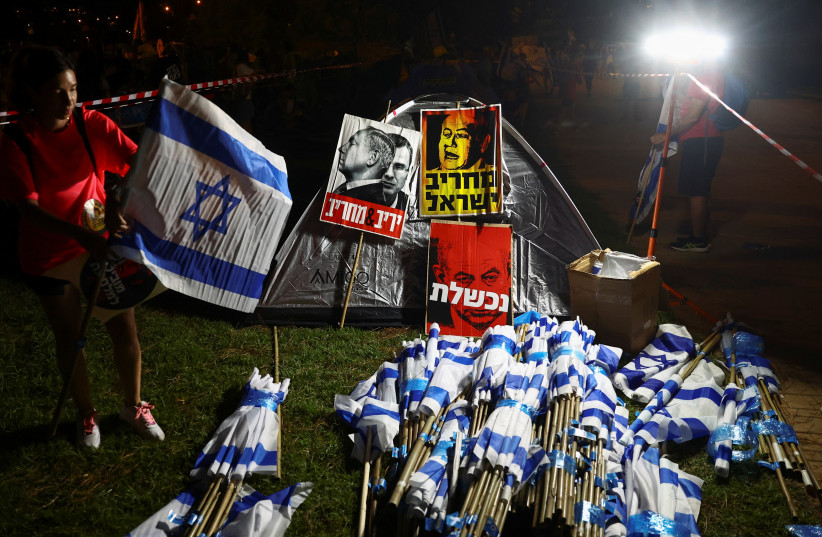Israeli flags and placards with pictures of Israeli Prime Minister Benjamin Netanyahu are seen as protesters against Netanyahu and his nationalist coalition government's judicial overhaul plans gather in a camp they set up near the Knesset building in Jerusalem July 23, 2023.  (credit: REUTERS/Ronen Zvulun)