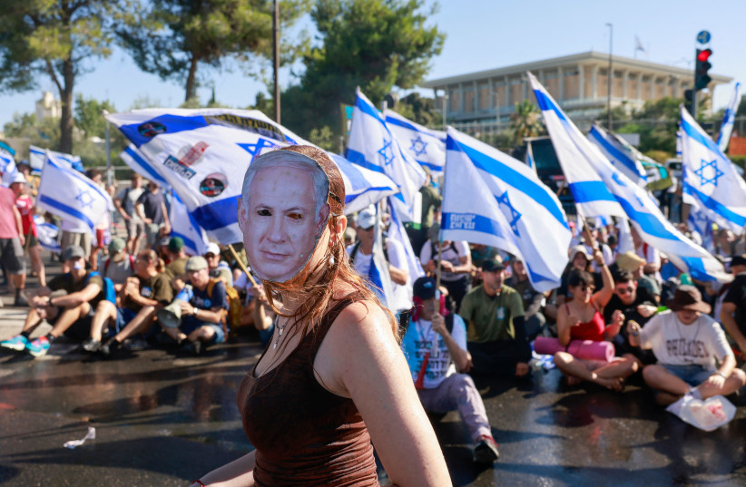  A demonstrator wearing a mask depicting Israel's Prime Minister Benjamin Netanyahu takes part in a sit-in to block the entrance of the parliament (Knesset) in Jerusalem on July 24, 2023, amid a months-long wave of protests against the government's planned judicial overhaul.  (credit: Menahem Kahana/AFP via Getty Images)