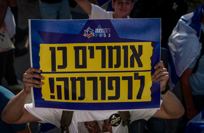  A supporter of the judicial overhaul legislation holds a sign reading ''Say yes to reform!'' at a pro-government rally in Tel Aviv on Sunday evening, July 23, 2023. (credit: AVSHALOM SASSONI/FLASH90)