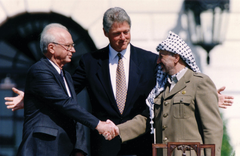  IN SEPTEMBER 1993, Yasser Arafat, then head of the PLO, agreed to a new division of the West Bank. He is seen here shaking hands with then-prime minister Yitzhak Rabin at the White House ceremony, as then-US president Bill Clinton looks on. (credit: GARY HERSHORN/REUTERS)