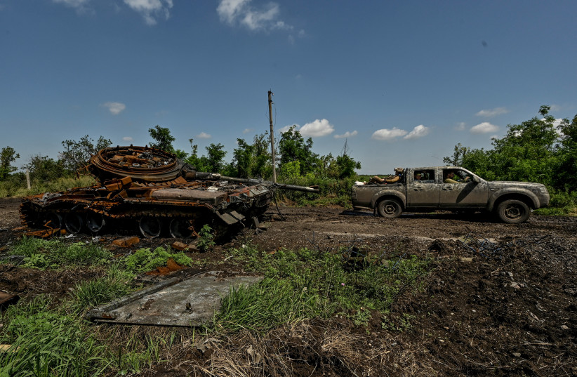  Ukrainian servicemen ride in a pick-up past a destroyed Russian tank is seen in the recently liberated village of Novodarivka, amid Russia's attack on Ukraine, in Zaporizhzhia region, Ukraine July 21, 2023. (credit: STRINGER/ REUTERS)