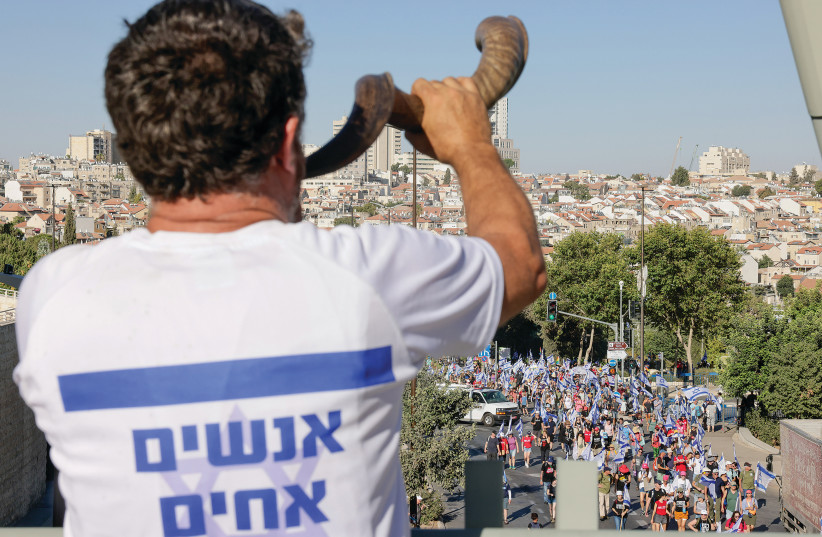  A MAN wearing a T-shirt with the slogan ‘We are all brothers’ blows a shofar near the Supreme Court in Jerusalem, calling for unity with the anti-reform demonstrators. (credit: MARC ISRAEL SELLEM/THE JERUSALEM POST)