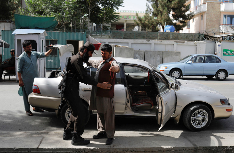 A Taliban soldier checks a man at a checkpoint in Kabul, Afghanistan, July 6, 2023.