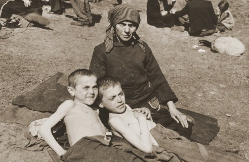  A woman and two children rest next to a stopped train after being liberated from the Nazis by the US Army in Germany in April 1945.  (credit: National Archives and Records Administration, College Park)