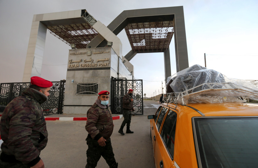  Members of Palestinian security forces keep watch as a taxi carrying passengers arrives at the gate of Rafah border crossing with Egypt, in the southern Gaza Strip February 23, 2021.  (credit: IBRAHEEM ABU MUSTAFA/REUTERS)