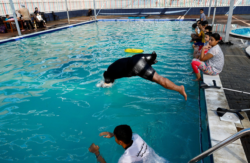  Majdi El-Tattar, a man with disability from Gaza trains children to swim as he became a high-in-demand swimming coach, in Gaza City August 5, 2023 (credit: REUTERS/IBRAHEEM ABU MUSTAFA)
