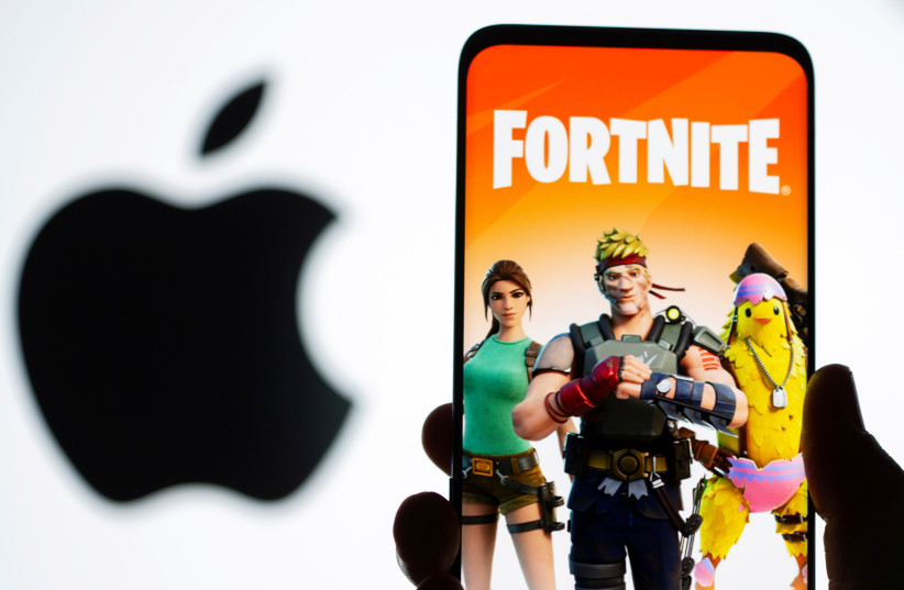  Fortnite game graphic is displayed on a smartphone in front of Apple logo in this illustration taken May 2, 2021. (credit: REUTERS/DADO RUVIC/ILLUSTRATION/FILE PHOTO)