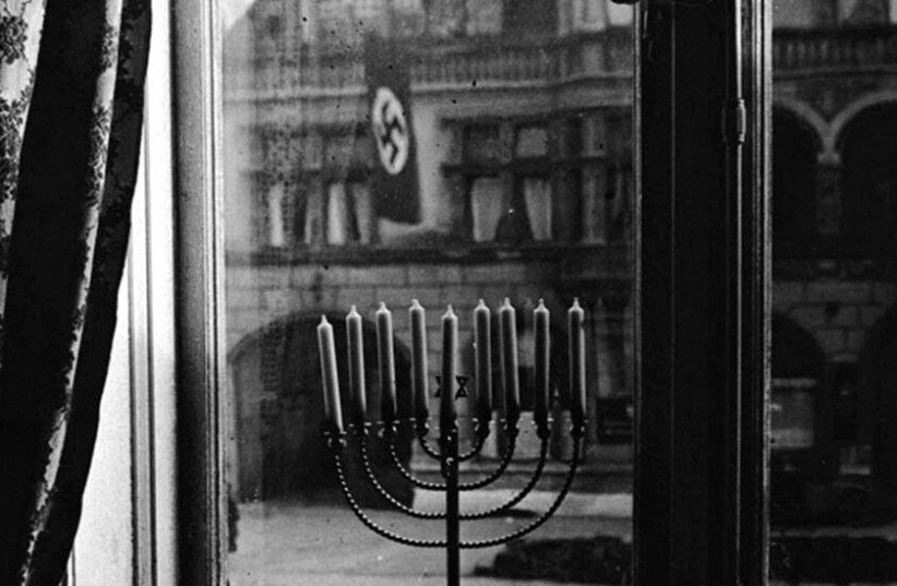  The iconic photo of a Hanukkah menorah with Nazi flags waving across the road, taken by Rachel Posner, wife of Rabbi Akiva Posner, in Kiel, Germany, 1931.  (credit: YAD VASHEM)