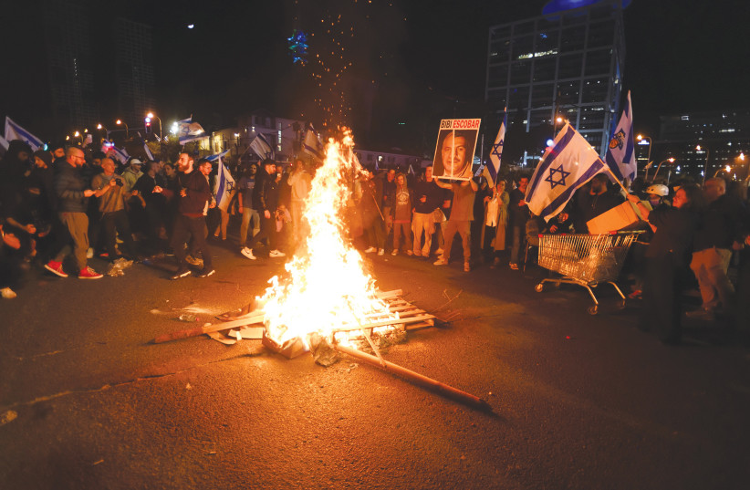 DEMONSTRATORS LIGHT a bonfire during an anti-judicial reform protest in Tel Aviv.