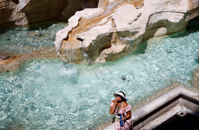 A woman cools off at Trevi fountain during hot weather as a heat wave hits Europe in Rome, Italy, July 19, 2022. (credit: GUGLIELMO MANGIAPANE / REUTERS)
