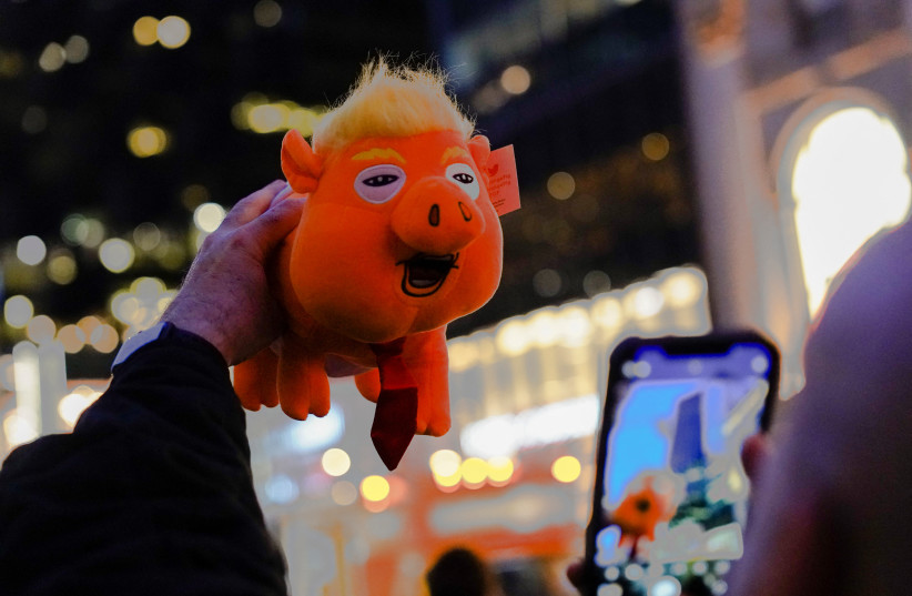 Guy Jacobson, of New York, photographs a plush toy depicting former U.S. President Donald Trump as an orange pig outside Trump Tower after Trump's indictment by a Manhattan grand jury following a probe into hush money paid to porn star Stormy Daniels, in New York City, U.S., April 3, 2023 (credit: BING GUAN/REUTERS)