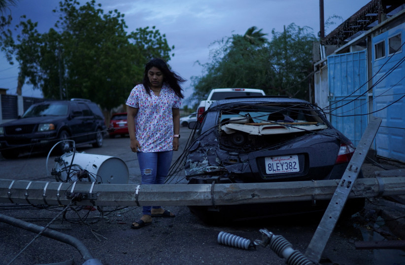  Laura Elizalde Reyes looks at a light pole that hit her car as Tropical Storm Hilary hits Baja California state, in Mexicali, Mexico, August 20, 2023. (credit: REUTERS/Victor Medina)