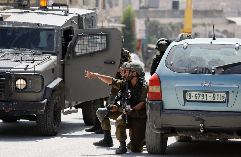 Israeli troops stand guard, near the scene of a shooting, near Hebron, in the West Bank August 21, 2023. (credit: MUSSA QAWASMA/REUTERS)