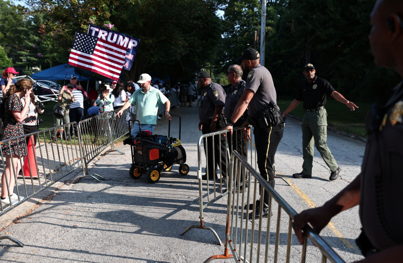  Law enforcement officers keep guard as supporters of former U.S. President Donald Trump gather at the entrance of the Fulton County Jail, while Trump is expected to turn himself in to be processed after his Georgia indictment, in Atlanta, Georgia, U.S., August 24, 2023. (credit: REUTERS/DUSTIN CHAMBERS)