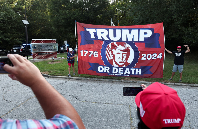  Supporters of former U.S. President Donald Trump hold a banner at the entrance of the Fulton County Jail, as he is expected to turn himself in to be processed after his Georgia indictment, in Atlanta, Georgia, U.S., August 24, 2023. (credit: REUTERS/DUSTIN CHAMBERS)